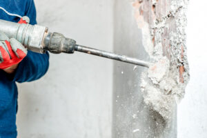 Man,Using,A,Jackhammer,To,Drill,Into,Wall.,Professional,Worker